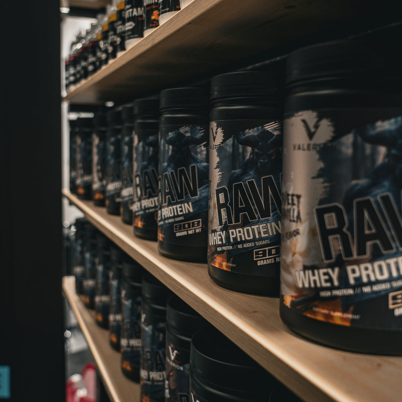 Shelves stocked with containers of raw whey protein powder.